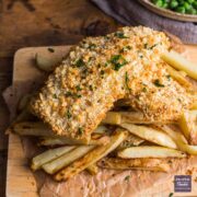 Two fillets of fish in golden bread crumbs sat on a pile of homemade oven chips
