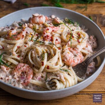 A bowl of linguine in a creamy sauce with salmon and prawns.