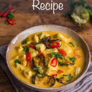 Thai red chicken curry in a bowl topped with sliced red chillies and with half a squeezed lime and extra sliced red chillies in the background.